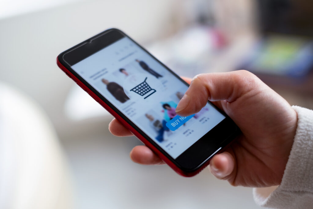 Image of a person holding a phone with a style app for clothing on the screen.